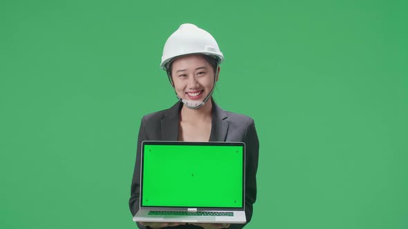 Asian Female Engineer With Safety Helmet Showing Green Screen Laptop In The Green Screen Studio