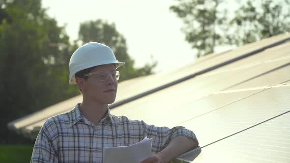 Engineer in a White Helmet Is at the Solar Power Station. Green Energy Concept alt