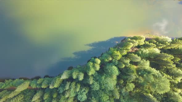 Top down aerial view of big lake with clear blue water between high mountain hills covered with