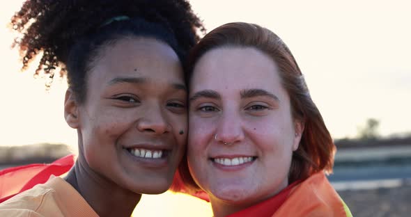 Happy lesbian couple smiling on camera at sunset