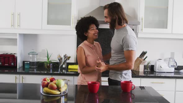 Mixed race couple dancing in the kitchen at home