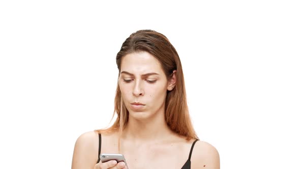 Displeased Young Beautiful Girl Looking at Phone Over White Background