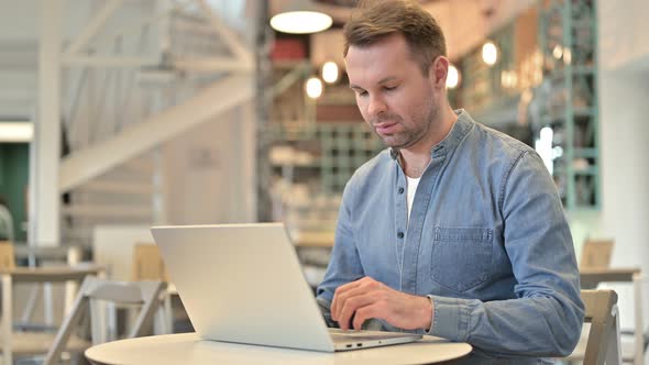 Positive Casual Man with Laptop Doing Thumbs Up in Cafe