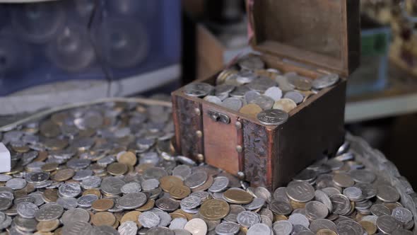 Opening the treasure box full of coins on pile of antique money