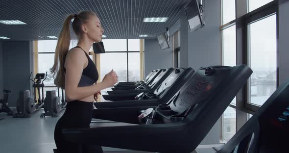 The Girl Goes In For Sports In The Gym. Running On A Treadmill 