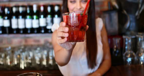 Portrait of barmaid serving cocktail at bar counter