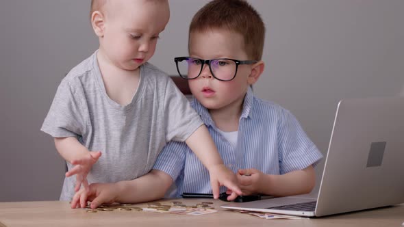 Caucasian Baby Boys Kids Playing with Money Coins Computer Laptop at Desk Table