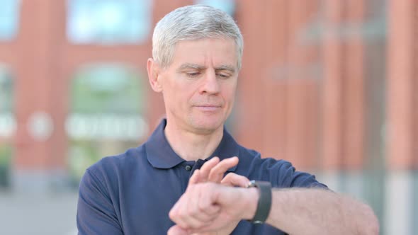 Outdoor Ambitious Middle Aged Man Using Smartwatch