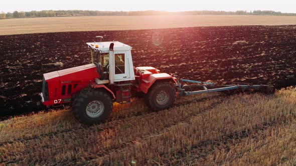 Tractor Plowing Fields, Preparing Land for Sowing. Aerial View. Farmer in Tractor Preparing Land in