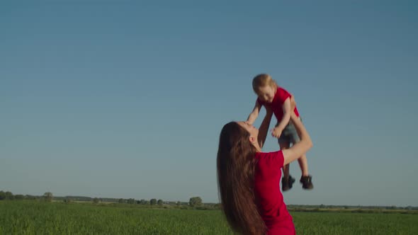 Mom Throwing Up Laughing Child in Summer Nature