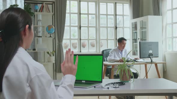 Asian Woman Doctor Having Video Conference On Laptop Computer With Mock Up Green Screen Display