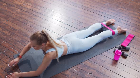 Young and sporty girl in sportswear is using resistance band while doing at home.