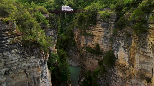 Aerial shot in between two rocky cliffs and canyons. With a river flowing in between them and lush g