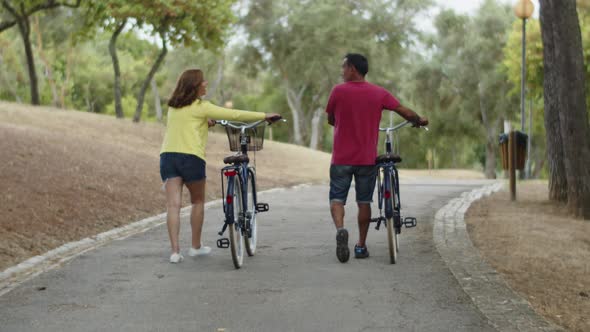 Long Shot of Caucasian Couple Walking with Bicycles in Summer