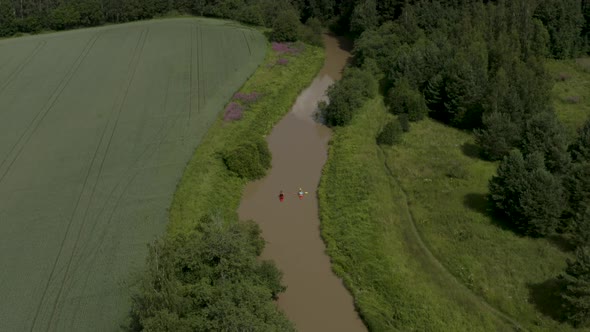 Beautiful aerial pan up of two people in colorful kayaks along the Keravanjoki River in Kerava, Finl