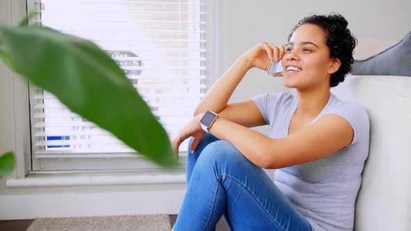 Happy woman talking on mobile phone in living room 4k