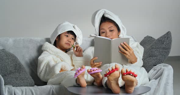 Young Asian Mother Relaxing on Sofa with Little Daughter Eating Cookies Sweets Girls Use Finger