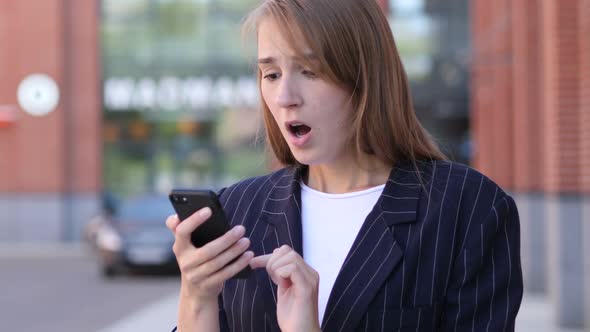 Business Woman Reacting to Loss While Using Smartphone Outside Office