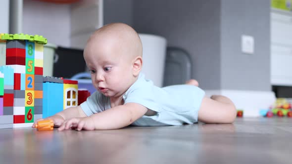 Little 6Month Infant Baby Trying to Crawl on the Wooden Floor Playing with Toys