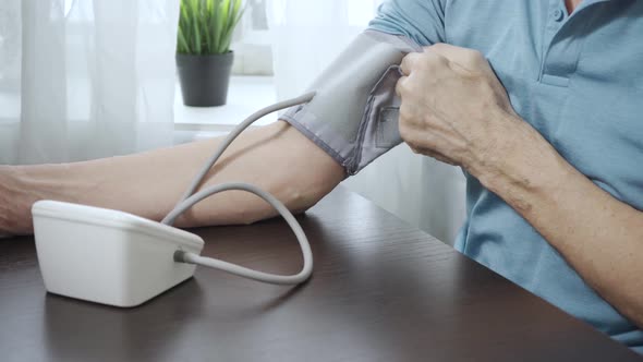 An Elderly Man is Measuring His Blood Pressure