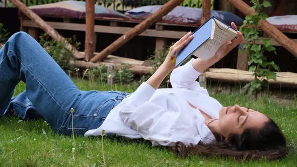 Woman Reading Book Lying on Lawn