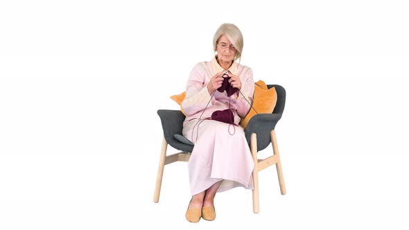 Intelligent Old Lady Knitting Sitting on a Chair on White Background.