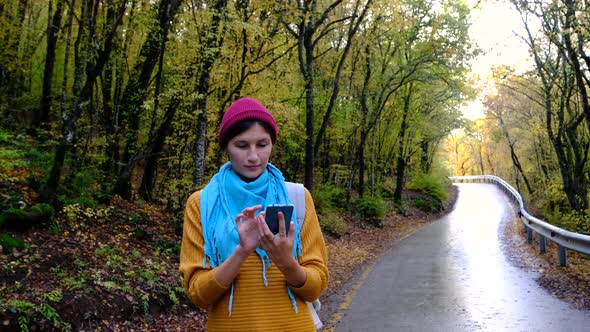 Woman with Backpack Using Smartphone Hiking In The Forest