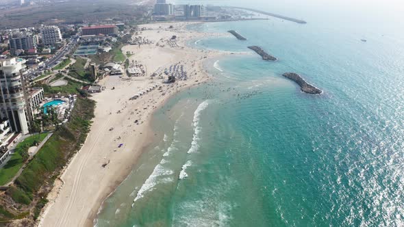 Long waves from the Mediterranean sea calmly roll over the extensive beaches while many people enjoy