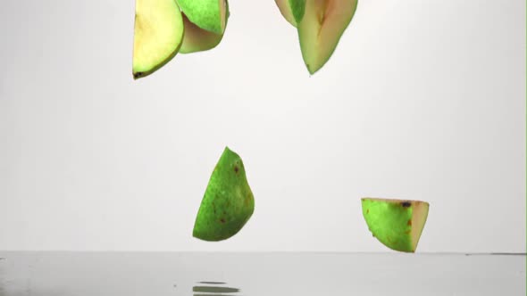 Super Slow Motion Pieces of Fresh Pear Fall Into the Water with Splashes