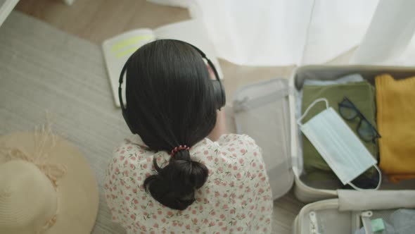 Travel Asian girl lying on the floor in the bedroom reading book and listening to music.