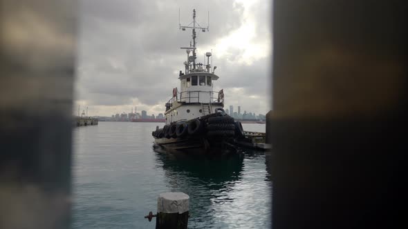 Push in of tug boat docked at pier through waterfront railing.