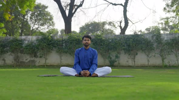 Butterfly Yoga Pose or Titliasana is being done by an Indian man in an Indian outfit