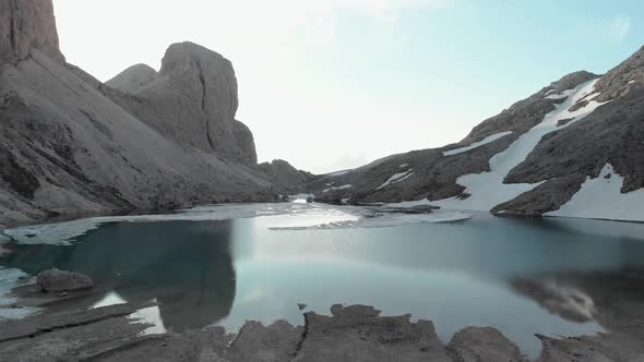 Drone Flying Forward to Alpine Lake Antermoia Covered in Ice in Dolomites Italy