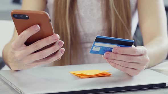 Young Woman Holding Her Plastic Card and Smart Telephone in Hand