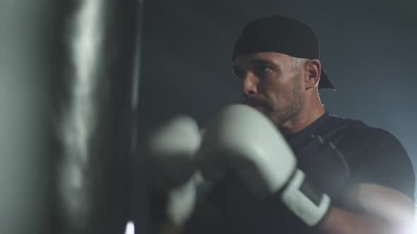 Portrait of a Disabled Man Fighter in Wheelchair Man Trains Punches on a Punching Bag Training in