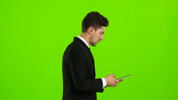Guy Looks at the Photo on the Phone and Finds a List of Pictures,. Green Screen. Side View