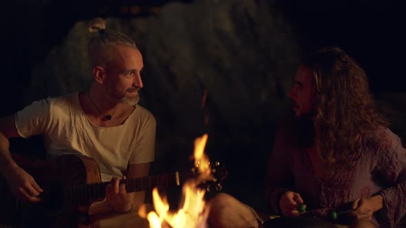 Friends Speaking Smiling Playing on Instruments Sitting Near Bonfire at Night Beach