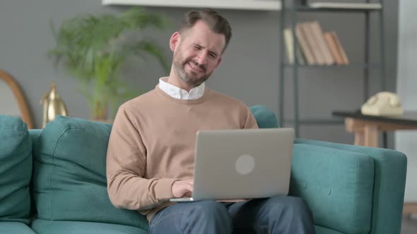Man with Laptop Having Neck Pain on Sofa