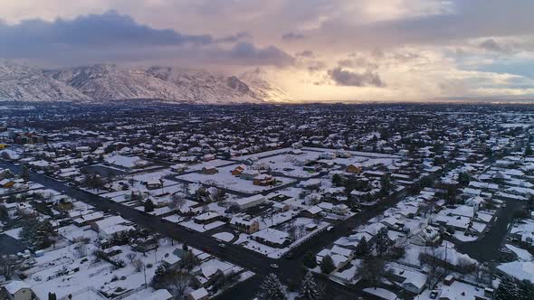 Flying over street intersection with snow covered town during sunset