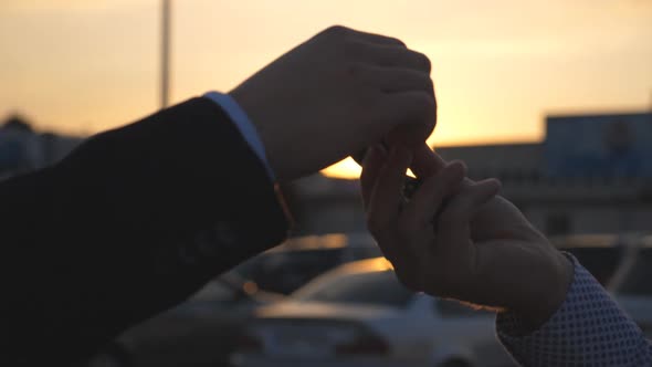 Male Hands Giving Keys of Car to His Friend with Sun Flare at Background