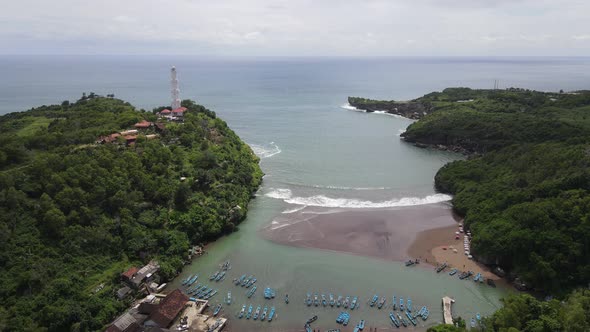 Aerial view of Baron beach in Yogyakarta, Indonesia with lighthouse and traditional boats