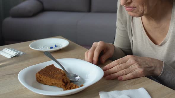 Senior Lady Feeling Heaviness and Stomach Pain After Eating Pie, Pills on Table