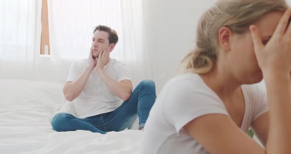 Caucasian attractive angry young couple having arguement topic fighting on bed in bedroom at home.