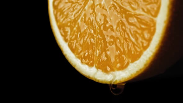 Sliced Orange Fruit with Drops of Juice Falling From It in Slow Motion. Closeup Macro Shot. Fresh