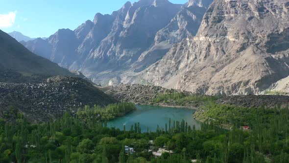 wide aerial view of a beautiful glacier blue lake called Upper Kachura Lake surrounded by a green fo