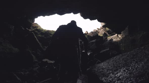 Man In Long Coat With Guitar Case Leaving Cave