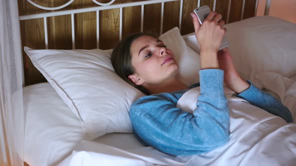 Woman in Bed Browsing on Smartphone at Night