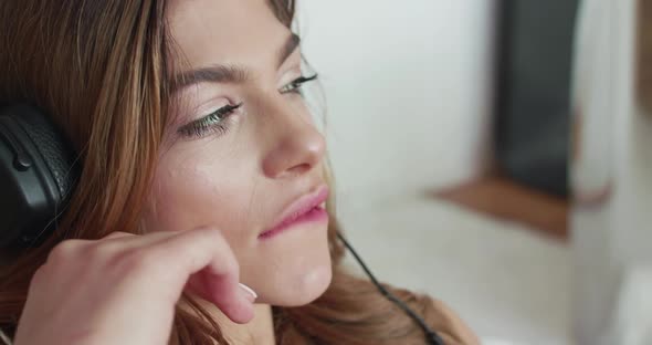 Woman with Headphones on Looks Seductively at Camera and Caresses Lip By Finger