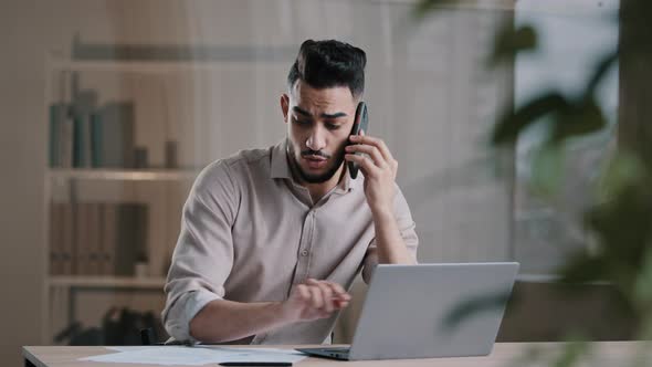 Busy Millennial Arabian Business Man Web Designer Employee Using Laptop Talking on Cell Phone