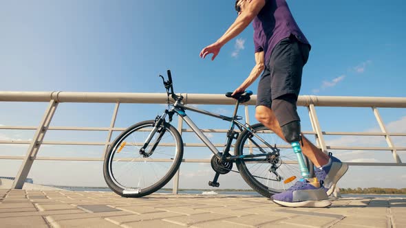 A Man with an Imitated Leg Is Walking Away with the Bike